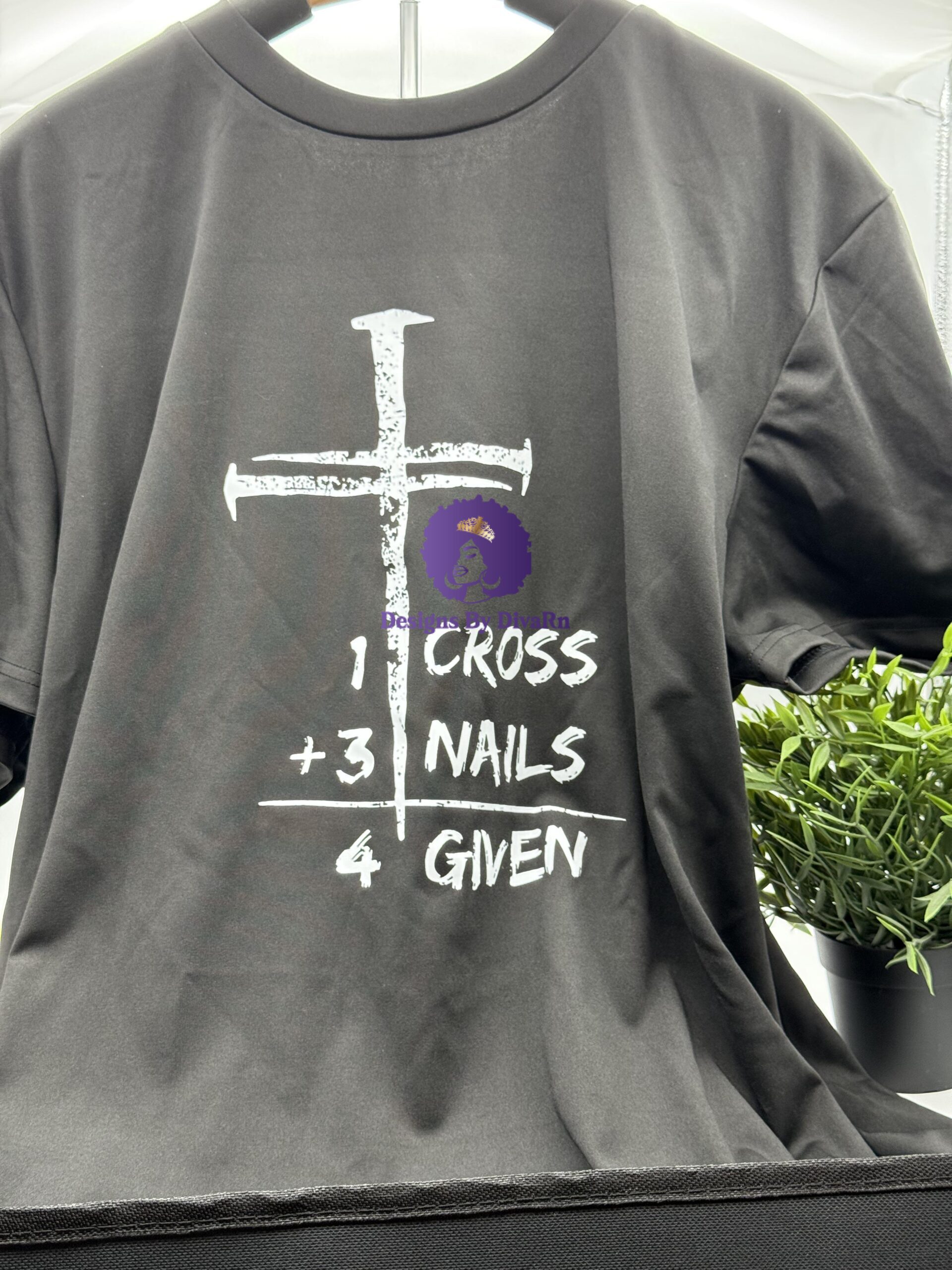 A black Christian t-shirt from Designs By DivaRn with a large, distressed white cross and the text '1 CROSS + 3 NAILS = 4 GIVEN', symbolizing forgiveness through Christ's sacrifice.