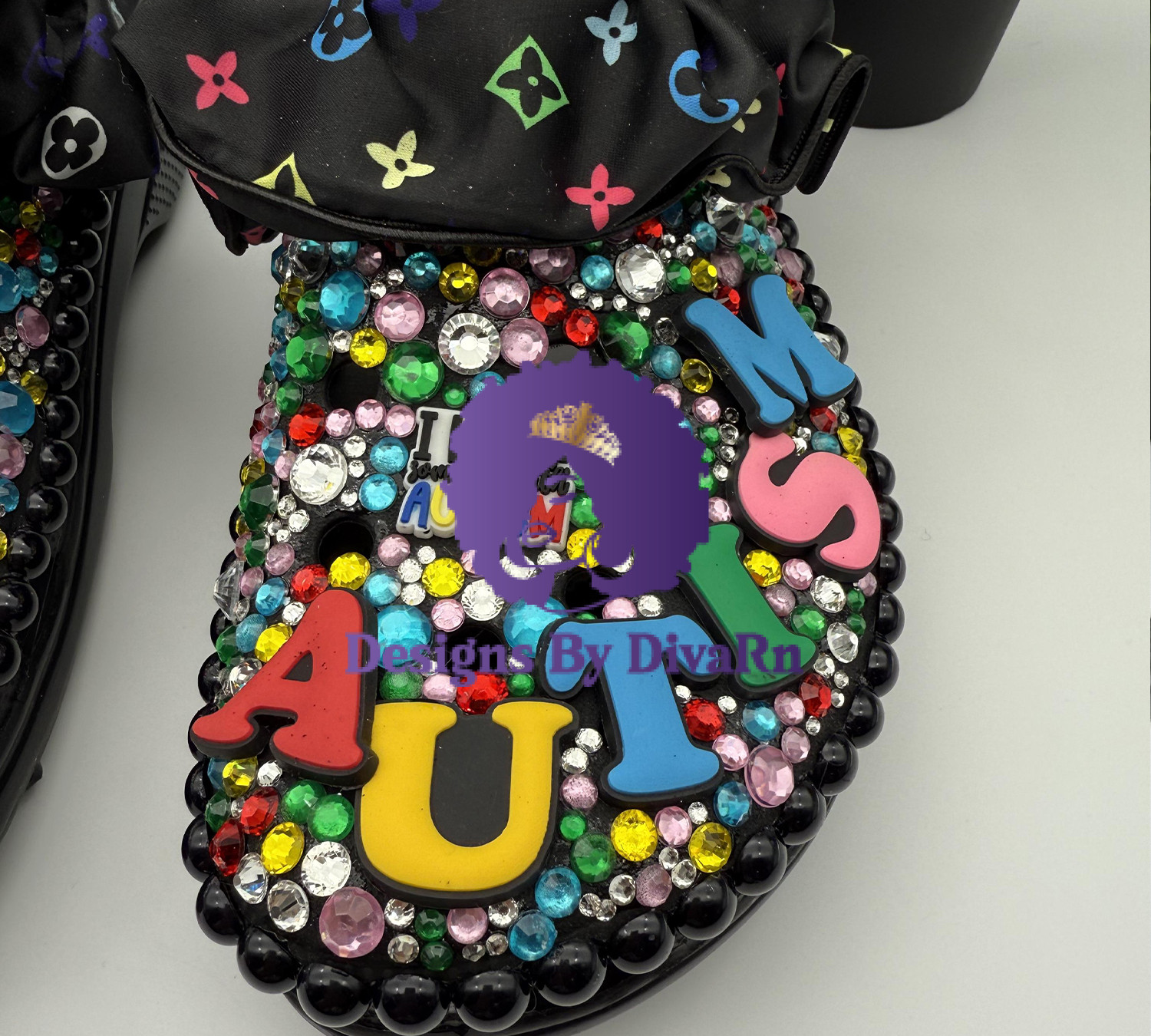 A customized black Croc for autism awareness, covered in colorful rhinestones, black beads, and 