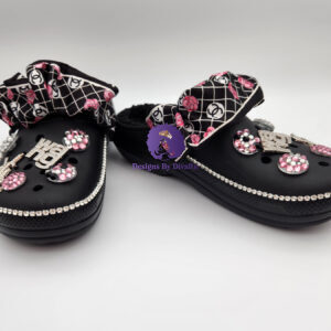 A pair of black custom clogs featuring a designer-inspired print bow strap, rhinestone