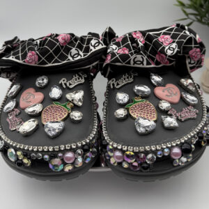 A pair of black custom clogs with a designer-inspired floral print bow strap, adorned with 