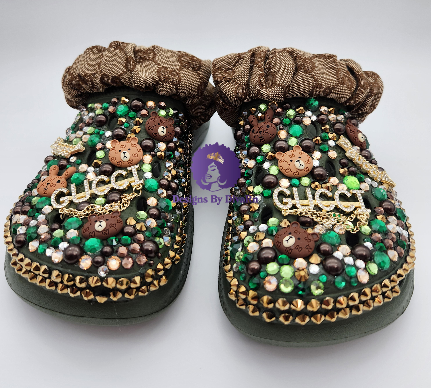 BLAGRECR-011 A pair of green custom clogs with designer-inspired teddy bear charms, a gold logo charm, green and gold rhinestones, and a monogrammed ruffled fabric strap.
