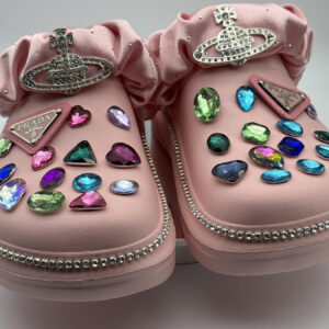 Pink clogs decorated with large, multicolored gems and a rhinestone border.