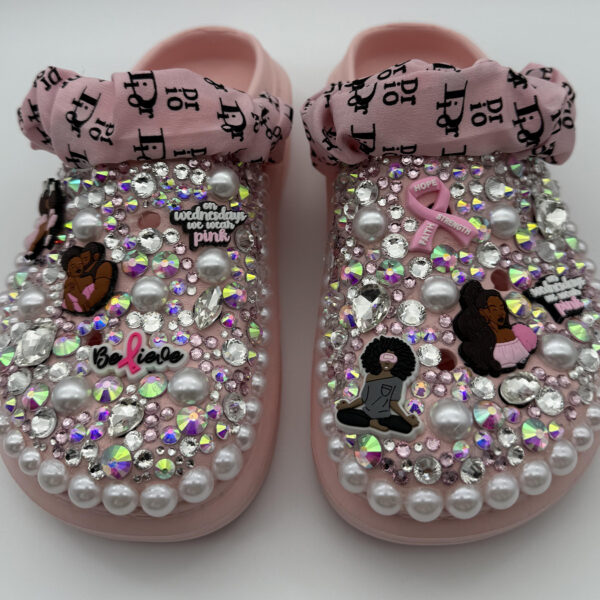 Pink clogs decorated with rhinestones, pearls, a pink ribbon, and a 