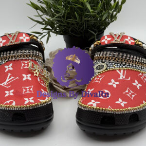 A pair of custom Lavish Monogram Clogs by Designs By DivaRn, featuring black clogs with a red and white monogram overlay, detailed with layered gold chains, pearls, and rhinestone trims, and a fully embellished heel strap.