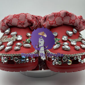 A pair of Red Bow Rhinestone Clogs by Designs By DivaRn, featuring custom red clogs with a red and pink designer-inspired monogram fabric bow, and lavishly decorated with large clear rhinestones, a red rose charm, and multi-colored crystal trim.