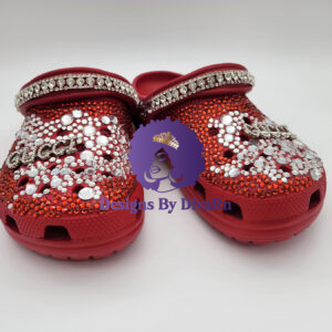 A pair of Rhinestone Script Clogs by Designs By DivaRn, showing red clogs completely encrusted with red and clear rhinestones that form a sparkling script logo, with a heel strap fully jeweled with large clear gems.