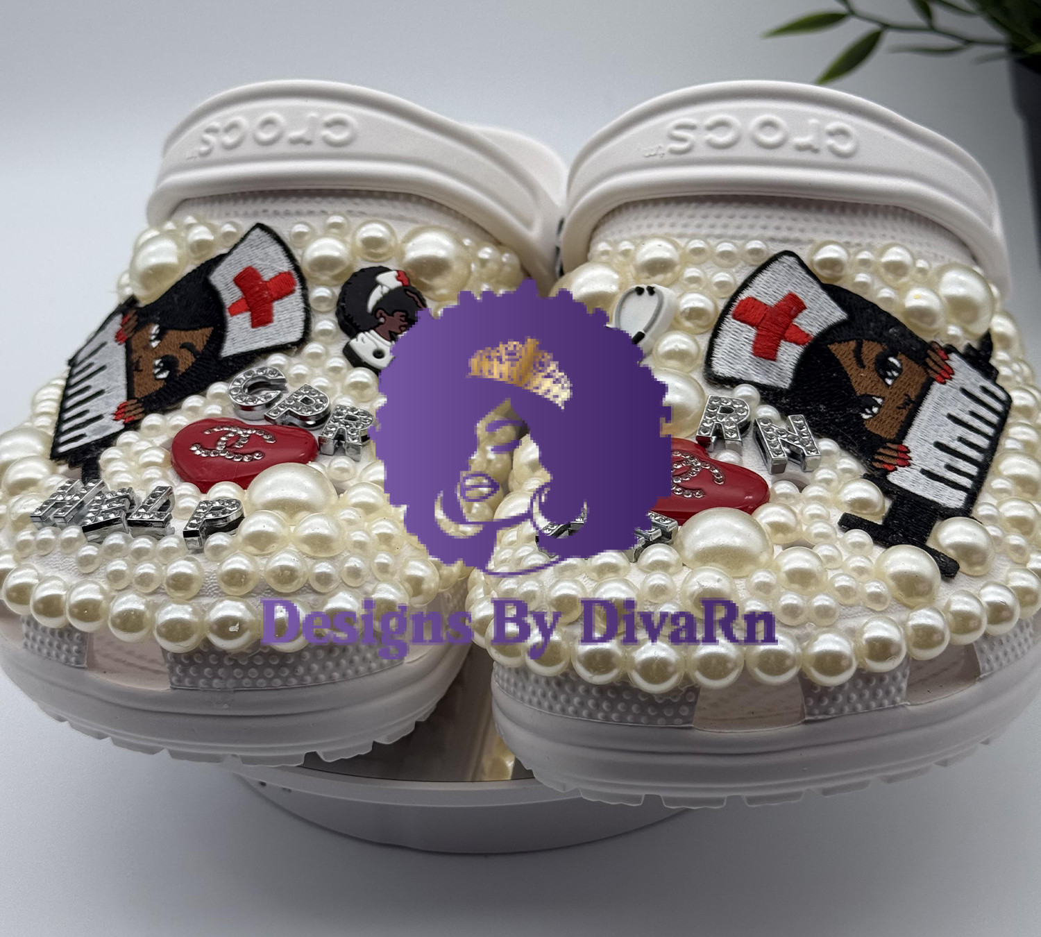 Custom white clogs decorated with pearls and healthcare-themed charms, including a dog dressed as a nurse.